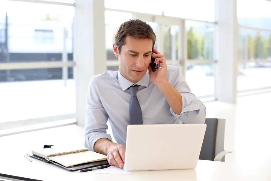 Mann telefoniert im Büro am Laptop