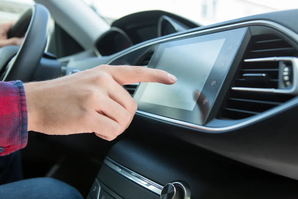 Finger tippt auf das Display im Auto